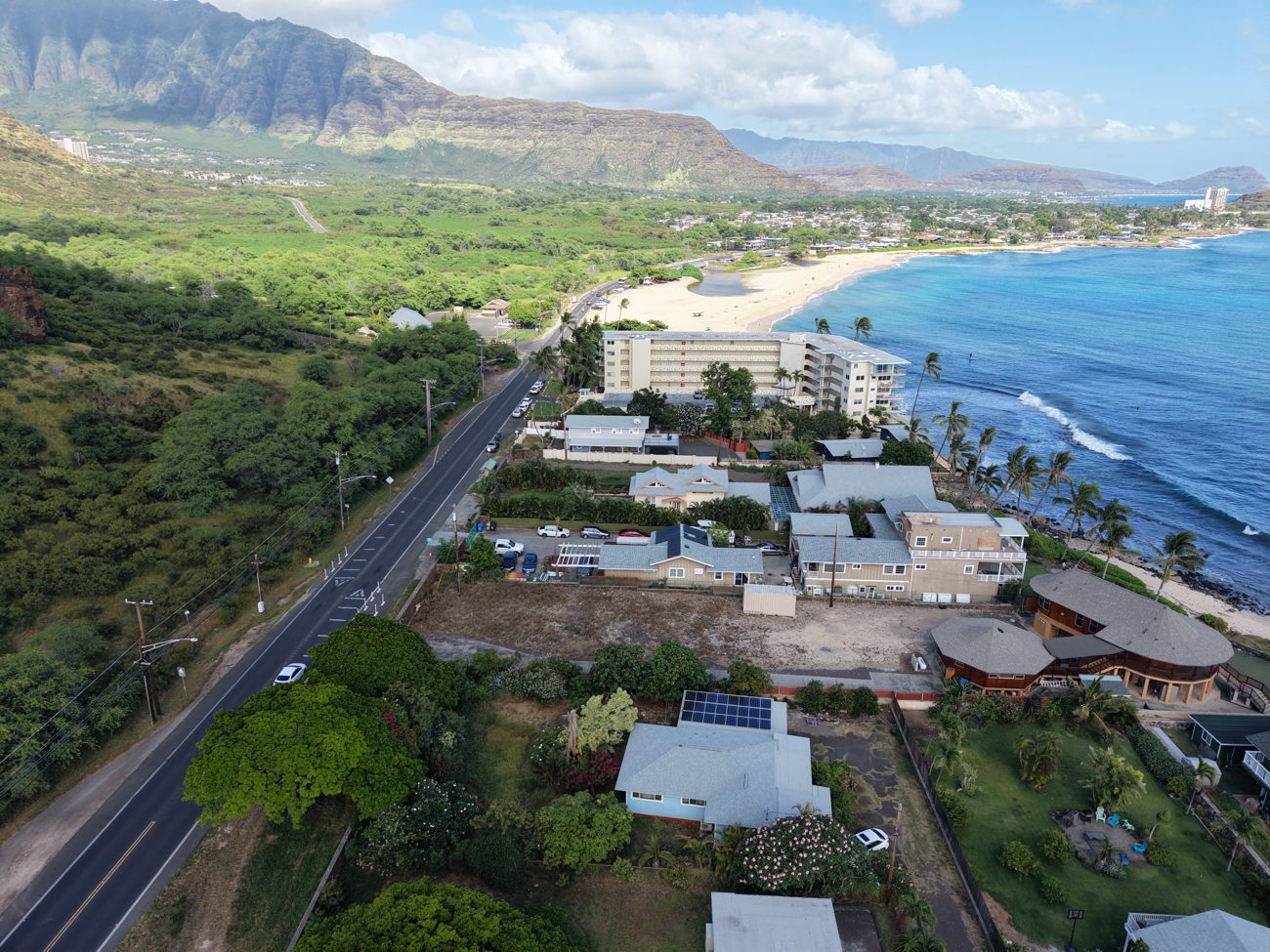 Aerial drone photo of an Oʻahu beachfront with town and mountains for a real estate listing